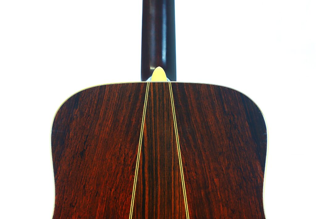 Close-Up Of The Back Of A Martin D-35 1979 Acoustic Guitar Featuring A Dark Wooden Finish, Yellow Binding, And Visible Neck, Set Against A White Background.