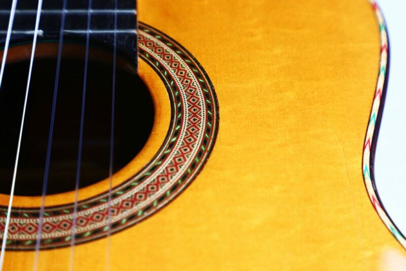 Nahaufnahme des Schalllochs und der Rosette der Andrés Marvi 2021 Negra Flamenco Guitar mit komplizierten dekorativen Mustern und einem Teil der schwarzen Saiten auf dem eleganten Holzkorpus.