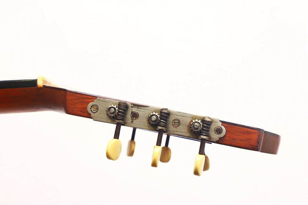Close-Up Of A Salvador Ibanez ~1900 Classical Guitar Headstock With Four Cream-Colored Tuning Pegs And Metal Gears On Warm Brown Wood, Set Against A Plain White Background.