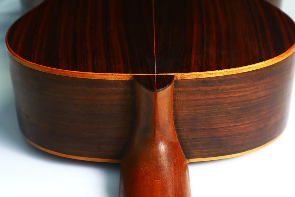 Close-Up Of The Back And Neck Joint On A Salvador Ibanez ~1900 Classical Guitar, Highlighting The Dark Polished Wood With Subtle Grain And Light-Colored Edges.