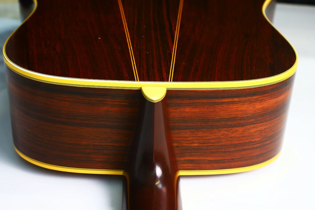 Close-Up Of The Back And Side Of A Martin D-35 1979 Acoustic Guitar, Showcasing Its Dark Wood Grain, Yellow Binding Along The Edges, Visible Neck Joint, And Glossy Finish.