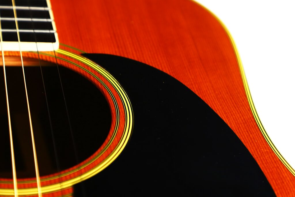Close-Up Of A Martin D-35 1979 Acoustic Guitar, Highlighting Its Wooden Body, Decorative Sound Hole Rings, Partial Pickguard, And Visible Strings On The Left Against A White Background.