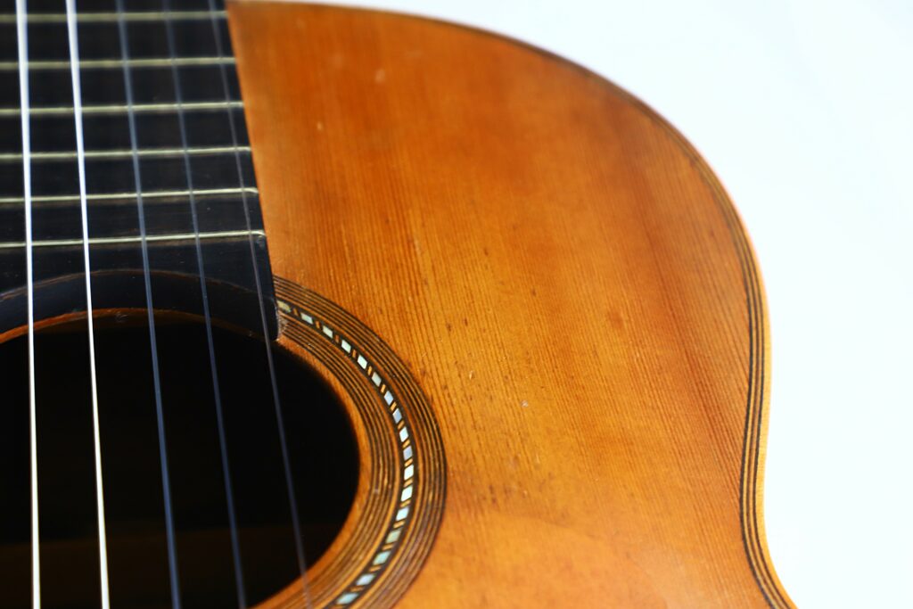 Close-Up Of A Salvador Ibanez ~1900 Classical Guitar, Highlighting The Strings, Fretboard, Wooden Body, And Decorative Inlay Around The Sound Hole Against A Light Background.