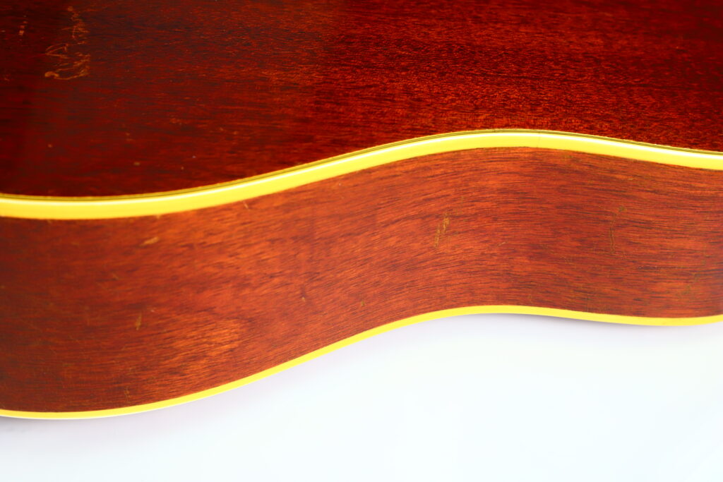 Nahaufnahme Der Seite Einer Gibson Hummingbird 1966 Akustik Gitarre, Die Die Holzmaserung Und Die Gelben Verzierungen Auf Weißem Hintergrund Hervorhebt.