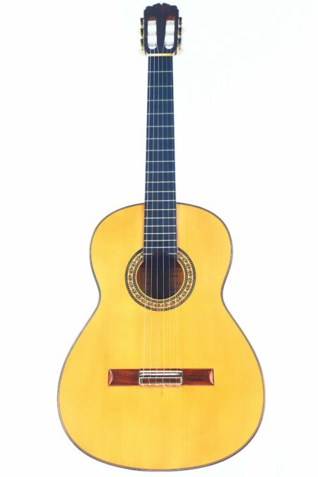 The Juan Miguel Gonzalez 2004 Flamenco Guitar features a light wood body, dark fretboard, and decorative rosette around the sound hole, shown against a white background.