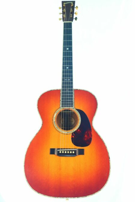 The Blazer & Henkes OM-42 1998 Acoustic Guitar features a sunburst finish, six strings, a black pickguard, and pearl fretboard inlays, displayed against a white background.