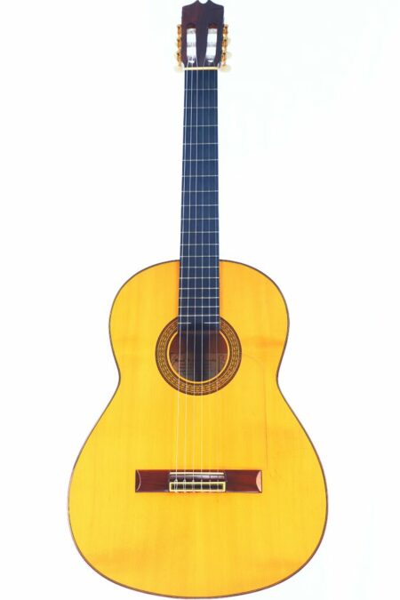 The Manuel Fernandez Fernandez 1990 Flamenco Guitar features a light wood body, dark fingerboard, and six strings, shown against a white background.