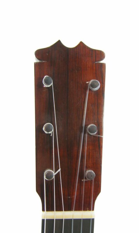 Nahaufnahme einer Gitarrenkopfplatte mit vier Stimmwirbeln und Saiten vor weißem Hintergrund. Das Holz hat ein dunkles Finish und die Stimmwirbel sind aus Metall.