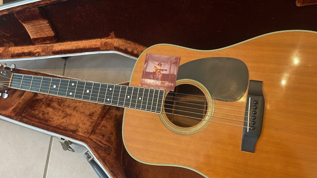 A Martin D-35 1979 Acoustic Guitar Rests In An Open, Plush-Lined Case, With A Small Photo Of A Musician Playing Guitar Placed Above The Strings Near The Sound Hole.