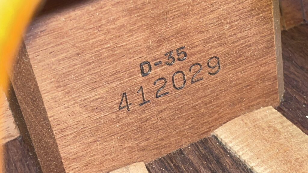 Close-Up Of The Interior Of A Martin D-35 1979 Acoustic Guitar, Showing A Wooden Surface Stamped With “D-35” And The Serial Number “412029” In Black Ink.