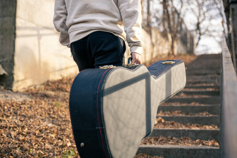 How To Maintain, Protect, And Store Your Guitar - A Person Carrying A Guitar In A Guitar Case