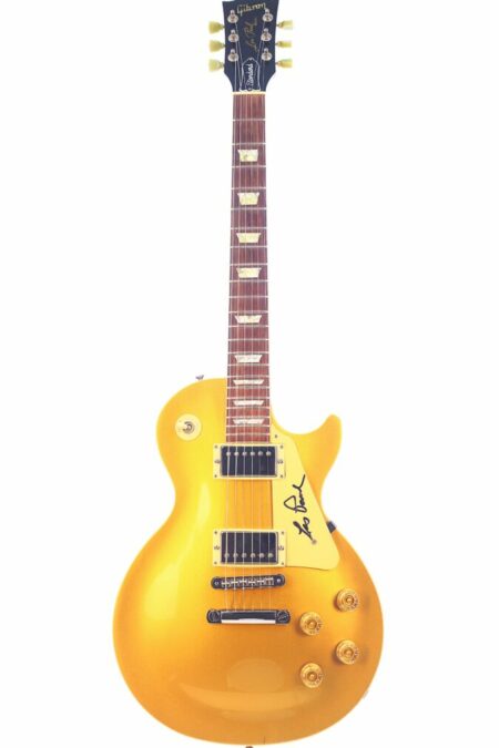 A Gibson Les Paul Standard 1989 Electric Guitar in gold with a single-cutaway body, white fretboard inlays, control knobs, and a black autograph near the pickups.