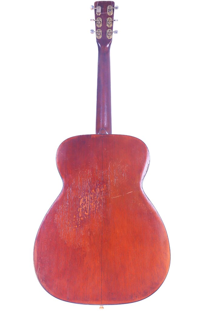 The Image Shows The Back View Of A Martin 00-18 1952 Acoustic Guitar With A Wooden Finish, Visible Grain, Some Scratches, And The Headstock With Tuning Pegs At The Top.