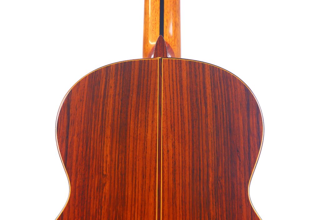 Close-Up Of The Back Of A Jose Ramirez 1A 1975 Classical Guitar, Featuring Polished Dark Wood, A Central Inlay Strip, And Visible Grain, Set Against A White Background.