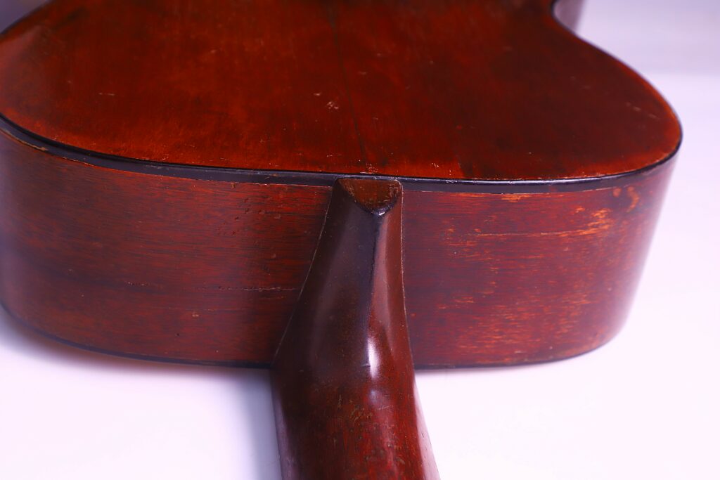 Close-Up View Of The Back Of A Martin 00-18 1953 Acoustic Guitar, Highlighting The Joint Where The Neck Meets The Body. The Guitar Features A Rich Brown Finish With Visible Wood Grain.