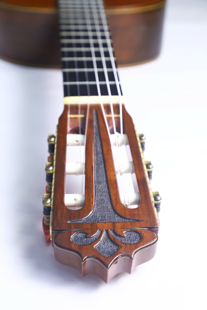 Close-Up Of The Yuichi Imai 1985 Classical Guitar Headstock, Featuring Tuning Pegs, Strings, And Detailed Woodwork, With The Neck Extending Into The Background On A White Surface.