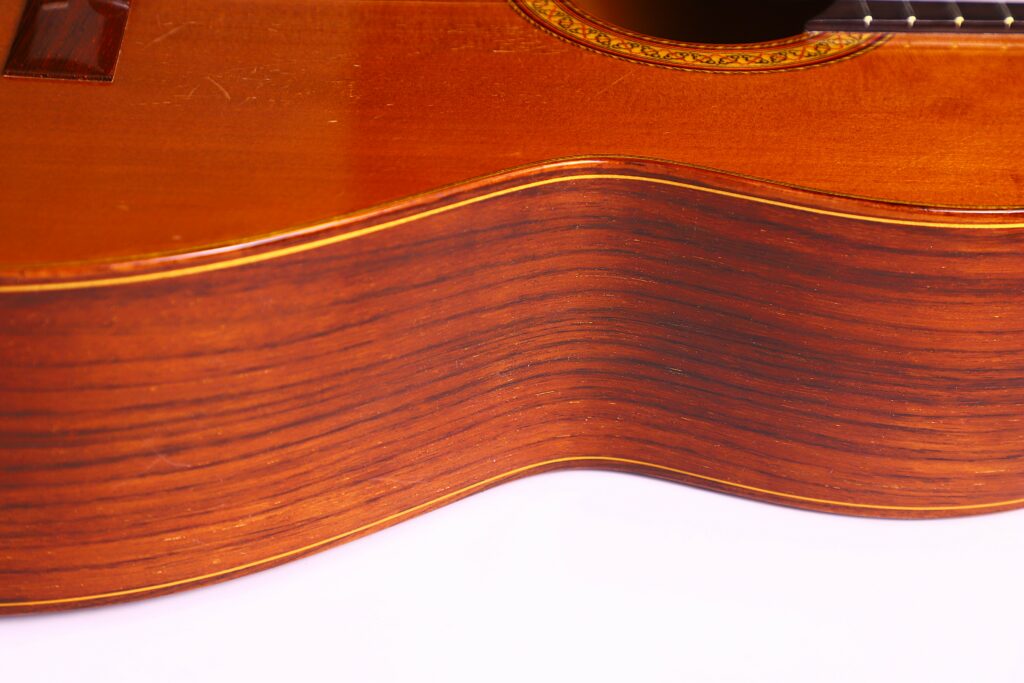 Close-Up Of The Side Of A Jose Ramirez 1A 1975 Classical Guitar, Highlighting Its Smooth, Curved Wooden Surface With Visible Wood Grain And A Polished Finish.