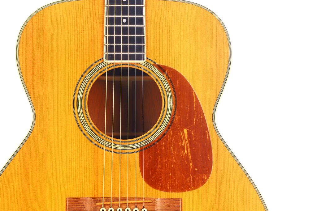 Close-Up Of A Martin M-38 1979 Acoustic Guitar Body, Highlighting The Sound Hole, Strings, Pickguard, And Part Of The Fretboard Against A White Background.