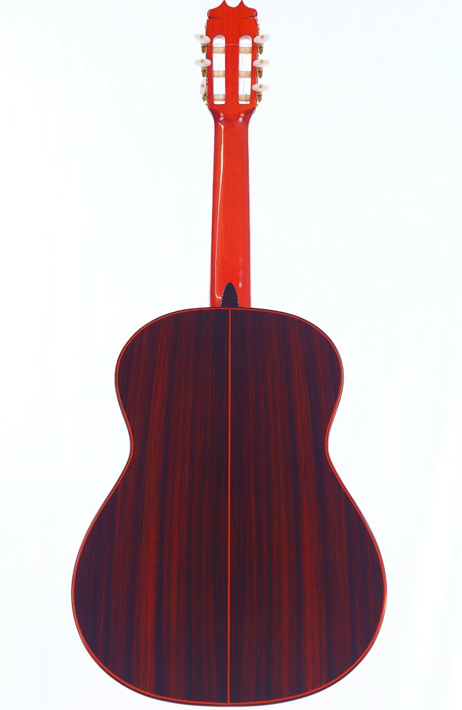 The Image Displays The Back Of A Hermanos Conde 1999 Paco De Lucia Special Flamenco Guitar With A Glossy Dark Wood Finish, Red Neck, And Gold Tuning Pegs Against A White Background.