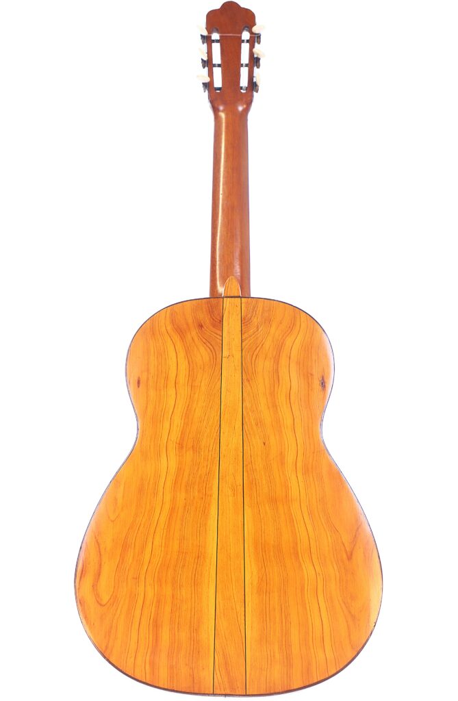 The Image Shows The Back View Of The Augustin Gaspar Cebrian 1935 Classical Guitar, Featuring A Smooth, Polished Wood Finish With Natural Grain Patterns. The Neck Extends Upward To A Headstock Fitted With Tuning Pegs.