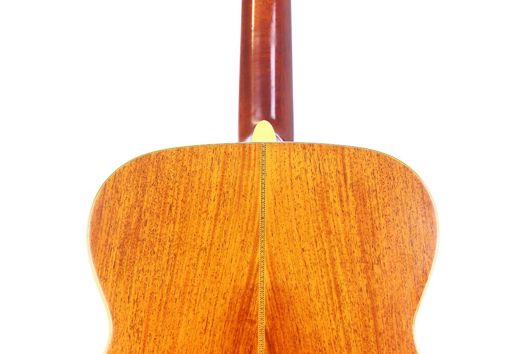 Close-Up Of The Back Of A Martin M-38 1979 Acoustic Guitar, Highlighting Its Polished Wooden Surface, Central Seam, And Lower Neck Against A White Background.