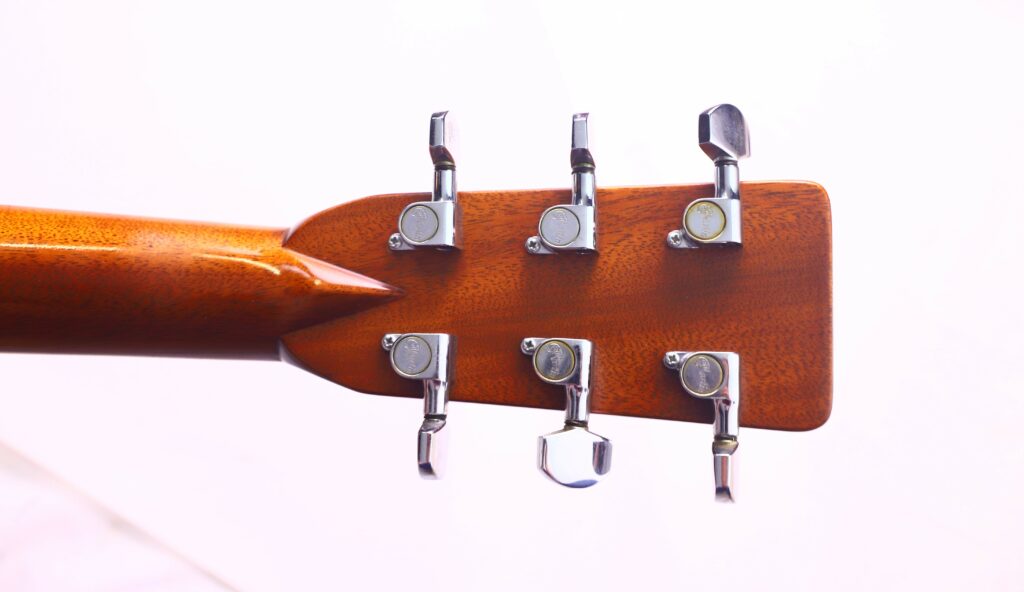 Close-Up Of The Back Of A Martin M-38 1979 Acoustic Guitar Headstock Showing Six Silver Tuning Pegs On A Wooden Neck, Set Against A Plain, Light Background.