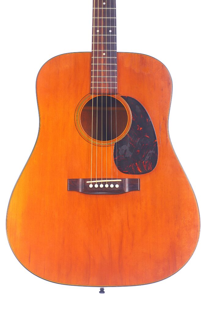 A Front View Of The Martin D-18 1967 Acoustic Guitar With A Natural Wood Finish, Six Strings, And A Black Pickguard, Photographed On A White Background.