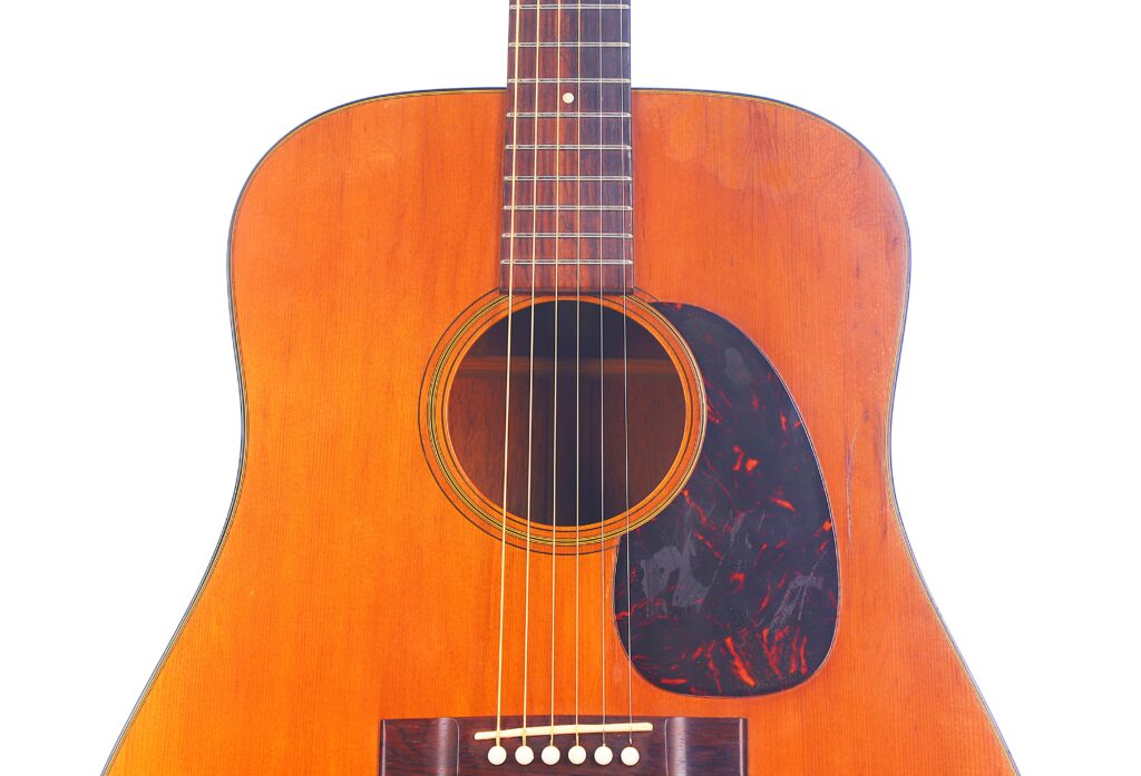 Close-Up Of The Body And Neck Of A Martin D-18 1967 Acoustic Guitar Featuring A Wooden Finish, Dark Pickguard, And Six Strings, Set Against A White Background.