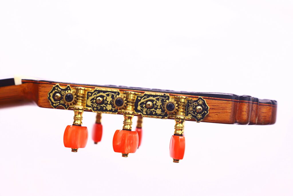 Close-Up Of The José Ruiz Pedregosa 2020 Classical Guitar Headstock Featuring Ornate Golden Tuning Pegs With Black Details And Four Bright Orange Tuning Knobs, Set Against A White Background.