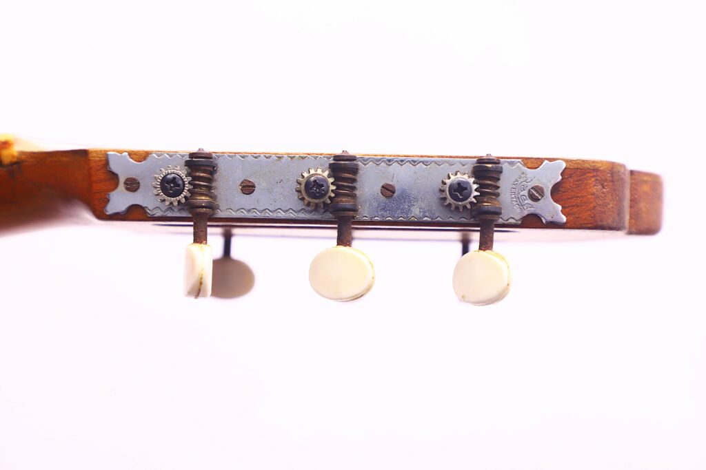 Close-Up Of The Tuning Pegs And Metal Tuning Plate On The Headstock Of An Augustin Gaspar Cebrian 1935 Classical Guitar Against A White Background.