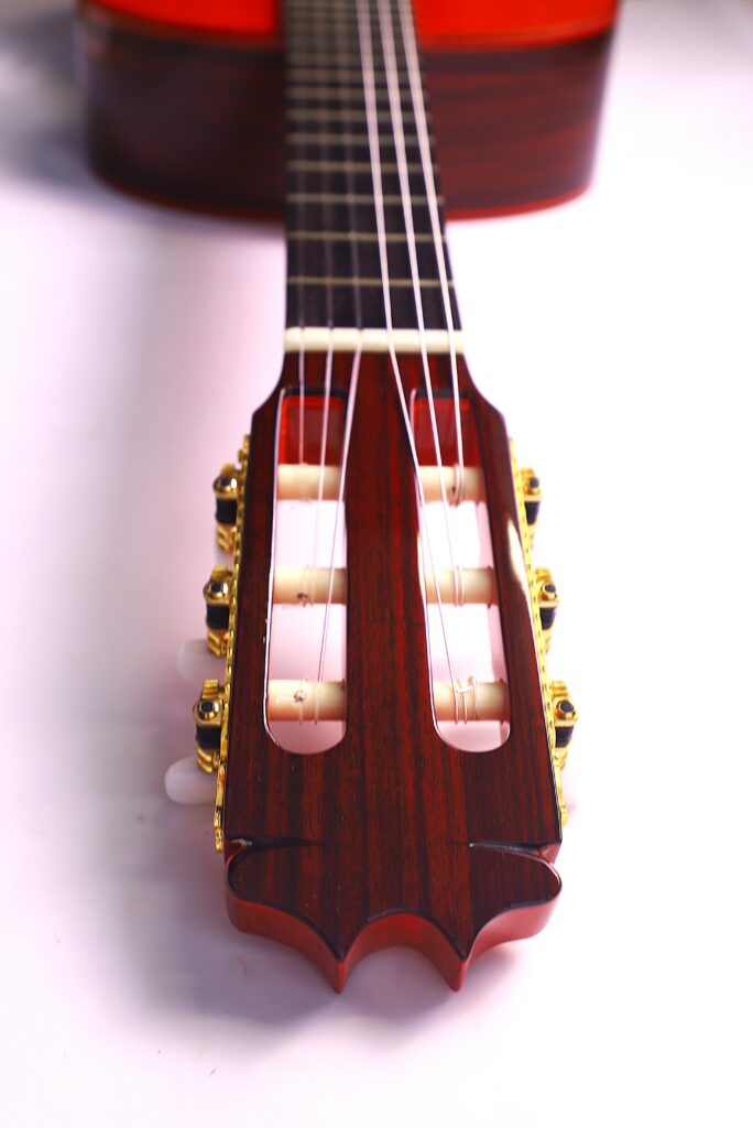 Close-Up Of The Hermanos Conde 1999 Paco De Lucia Special Flamenco Guitars Headstock And Tuning Pegs With Nylon Strings And Wooden Finish, Shot From Neck To Body On A White Background.