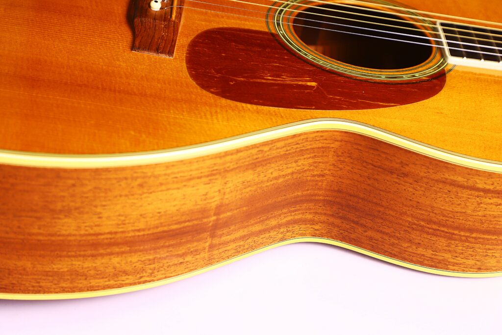 Close-Up Of A Martin M-38 1979 Acoustic Guitar Highlighting The Wooden Body, Soundhole, And Strings With Emphasis On The Wood Grain And Texture Against A Light Background.