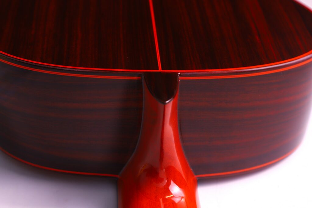 Close-Up Of The Back And Neck Joint Of A Hermanos Conde 1999 Paco De Lucia Special Flamenco Guitar, Featuring Polished Dark Wood With Red-Brown Hues, Fine Grain, And Red Trim.