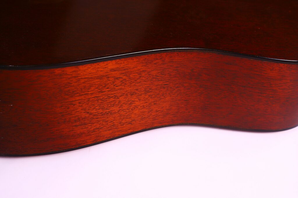 Close-Up Of The Side Of A Martin D-18 1967 Acoustic Guitar, Highlighting Its Smooth, Polished Brown Wood Grain And Elegant Curves Against A Light Background.