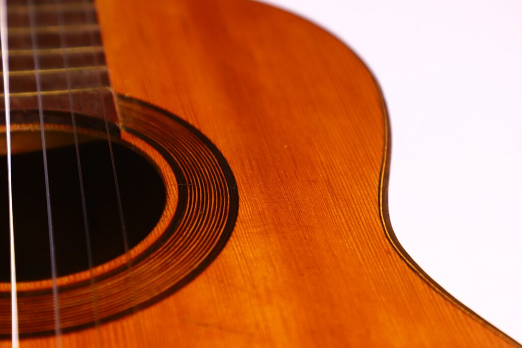 Close-Up Of The Augustin Gaspar Cebrian 1935 Classical Guitar, Highlighting Its Strings, Sound Hole, And Warm Brown Wooden Body Set Against A White Background.
