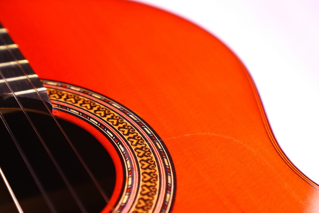 Close-Up Of The Hermanos Conde 1999 Paco De Lucia Special Flamenco Guitar, Highlighting Its Strings, Ornate Sound Hole Rosette, And Smooth Orange-Toned Wooden Body.