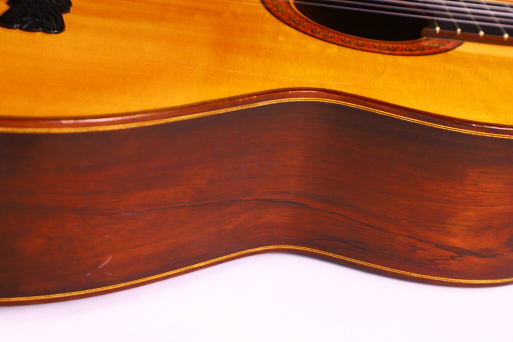 Close-Up Of The Side Of A José Ruiz Pedregosa 2020 Classical Guitar, Showcasing Its Wooden Body With A Glossy Finish That Highlights The Natural Grain And Texture.