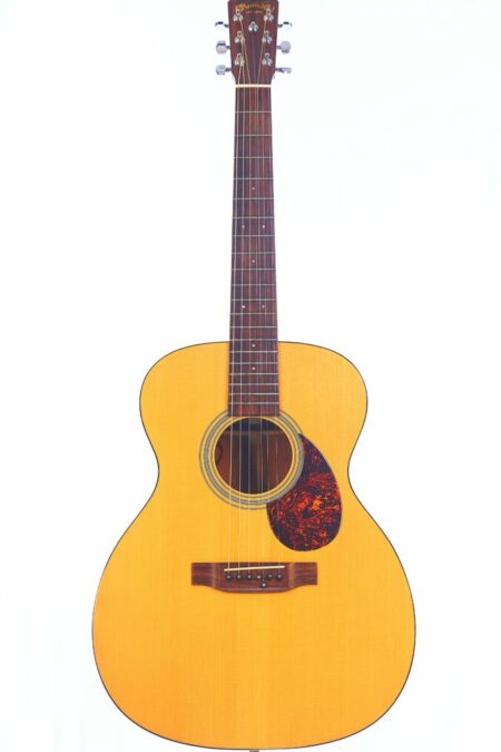 A full view of the Martin OM-21 Custom 7-String Acoustic Guitar featuring a natural wood finish, seven strings, a round sound hole, and a tortoiseshell-patterned pickguard, set against a white background.