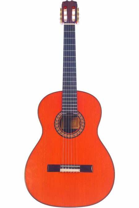 The Hermanos Conde 2000 Negra Flamenco Guitar features a bright orange body, black fretboard, and nylon strings, displayed upright against a white background.