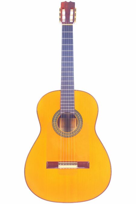 The Hermanos Conde 1986 Paco de Lucia Flamenco Guitar features a light wood body, dark fingerboard, and six strings, displayed upright on a white background.