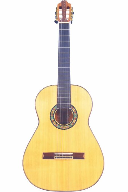 The Pedro Fernández Luque 2024 Negra Flamenco Guitar features a light wooden body, dark fretboard, and a colorful rosette around the soundhole, elegantly displayed against a white background.