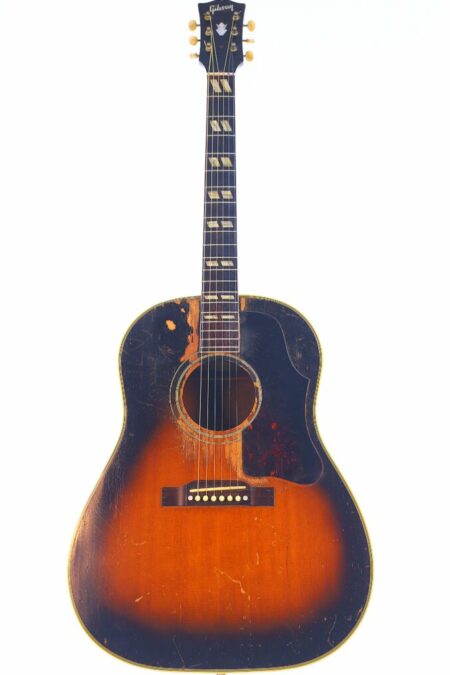 A Gibson Southern Jumbo 1955 Acoustic Guitar with a sunburst finish, showing visible wear and scratches on the sound hole and body, is photographed against a plain white background.