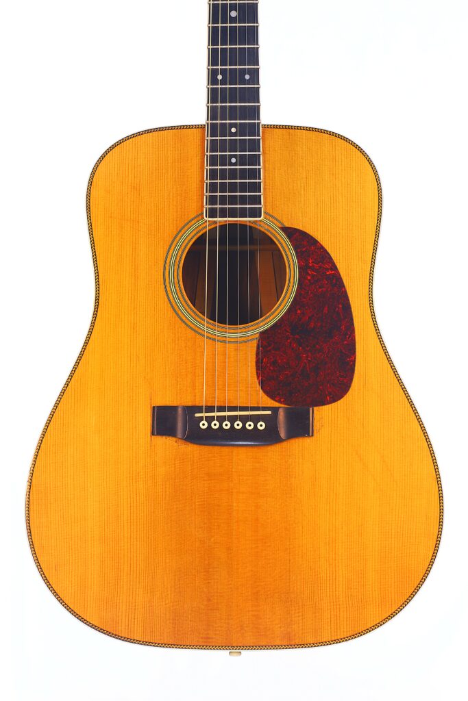 A Close-Up Of The Martin Hd-35 1979 Acoustic Guitar, Featuring A Natural Wood Finish, Dark Pickguard, Six Strings, And Visible Frets, Photographed Against A White Background.