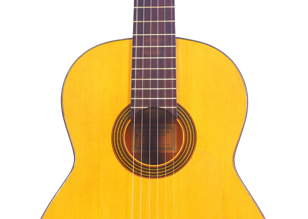 A Close-Up Of The Conde Hermanos 1971 Flamenco Guitar’s Front, Highlighting Its Wooden Body, Ornate Rosette Around The Sound Hole, And Six-Stringed Lower Neck.