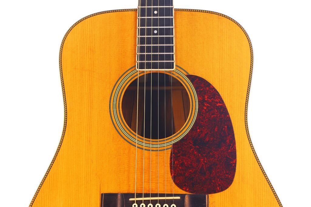 Close-Up Of A Martin Hd-35 1979 Acoustic Guitar Featuring The Body, Sound Hole, Part Of The Neck, And A Reddish-Brown Pickguard On A Light Wood Finish Against A White Background.