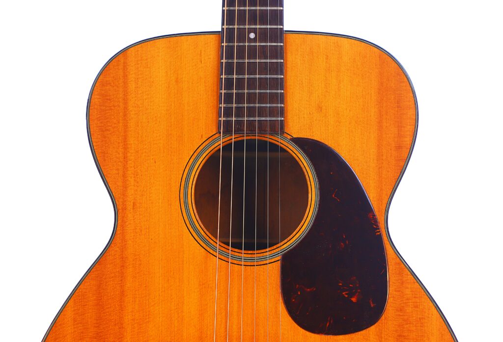 Close-Up Of A Martin 000-18 1950 Acoustic Guitar, Featuring A Natural Wood Finish, Visible Strings, Sound Hole, And Dark Pickguard Against A White Background.
