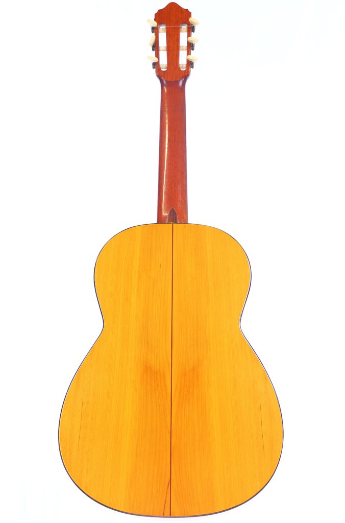 The Image Shows The Back View Of A Conde Hermanos 1971 Flamenco Guitar, Featuring A Wooden Body With A Polished Finish, And Displaying Its Neck And Tuning Pegs At The Top.