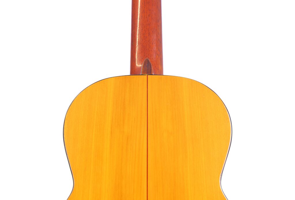 Close-Up Of The Back Of A Conde Hermanos 1971 Flamenco Guitar, Featuring A Glossy Wooden Surface With A Center Seam And Part Of The Neck, Set Against A White Background.
