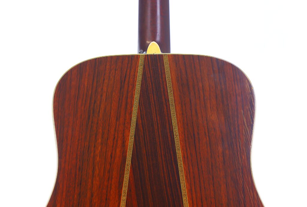 Close-Up Of The Back Of A Martin Hd-35 1979 Acoustic Guitar, Highlighting The Wood Grain, Decorative Center Strip Inlay, And Smooth Polished Finish Against A White Background.
