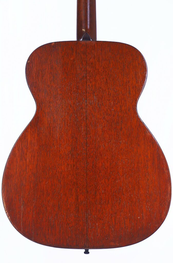 The Back View Of The Martin 000-18 1950 Acoustic Guitar Features A Smooth, Reddish-Brown Wooden Finish With Visible Wood Grain, Photographed Against A White Background.